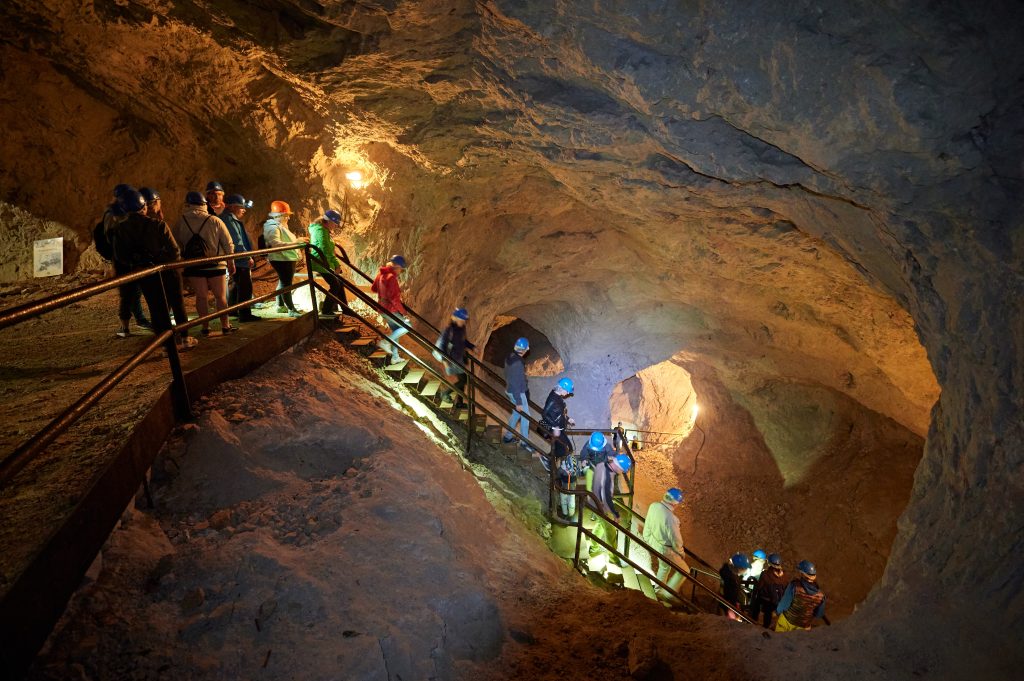 Visitors wearing protective helmets explore the mighty tunnels of the former mine and learn the story of mining.