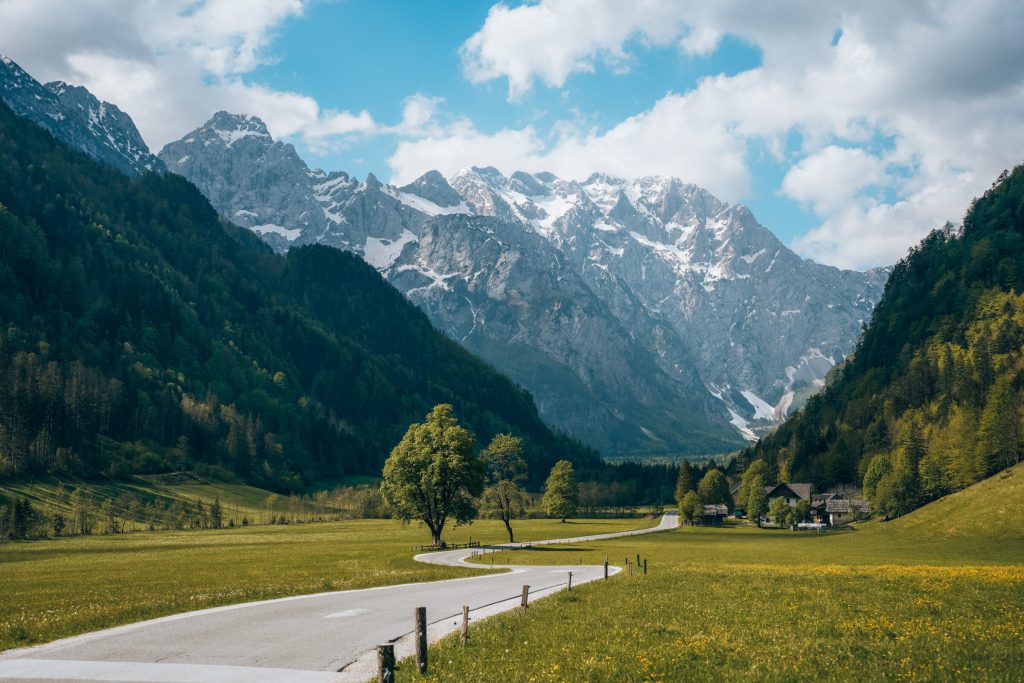 Green valley beneath the majestic peaks of the Kamnik-Savinja Alps, with a farm in the background