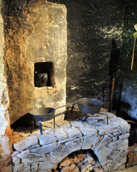 A black kitchen in Prežihov's Cottage with a preserved hearth and traditional furnishings of a former Koroška homestead.