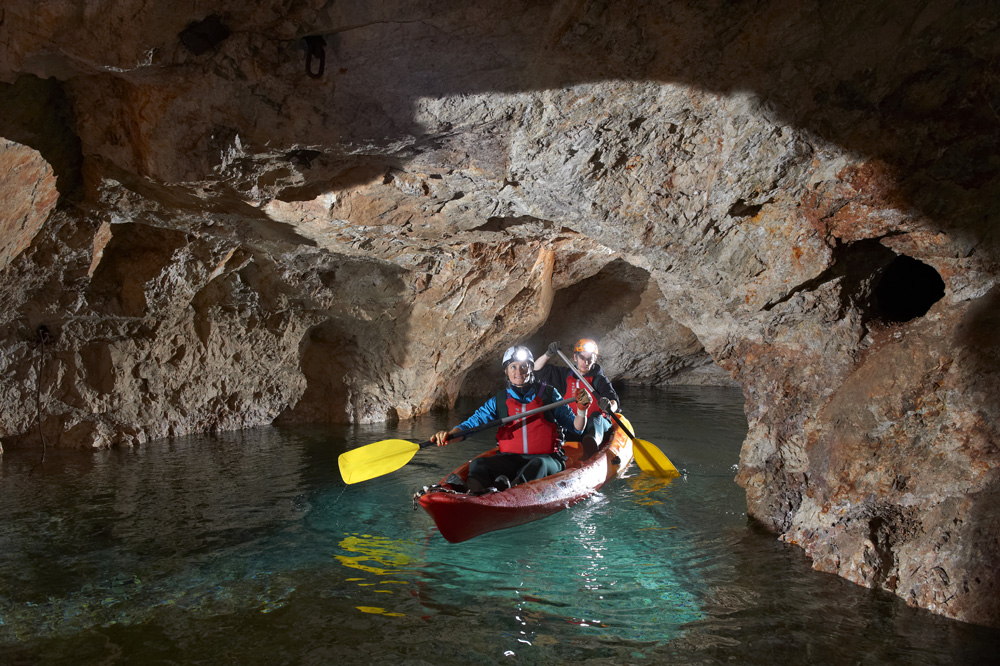 Two visitors kayaking through the flooded mining tunnels of the Peca Underworld.