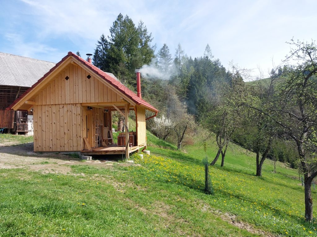 The wooden holiday house is nestled in a green rural environment, surrounded by meadows, fruit trees, and forests.