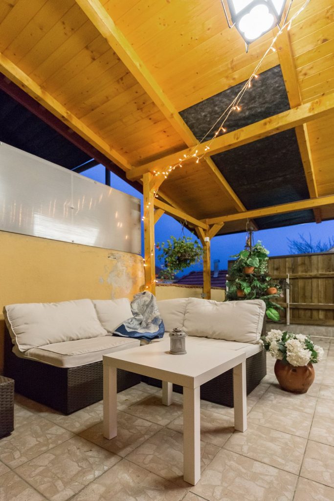 Pleasant outdoor corner with comfortable seating, wooden pergola, and lighting.