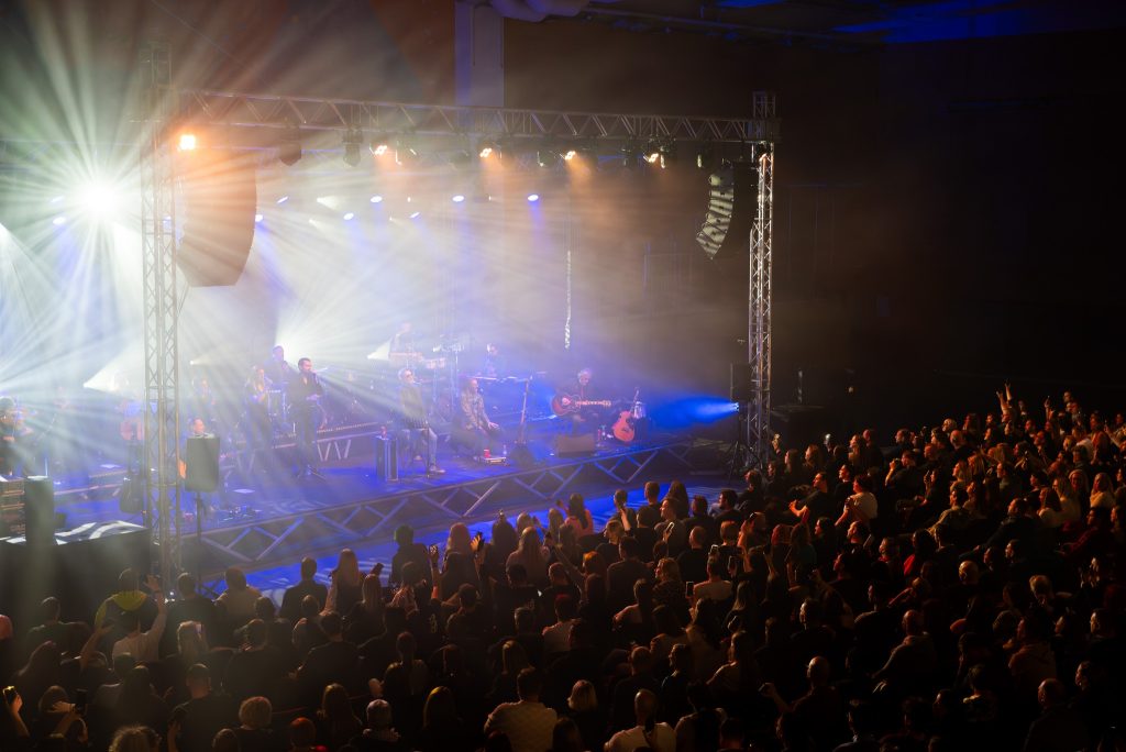 A musical evening with a stage performance, lighting effects and a crowd of visitors.