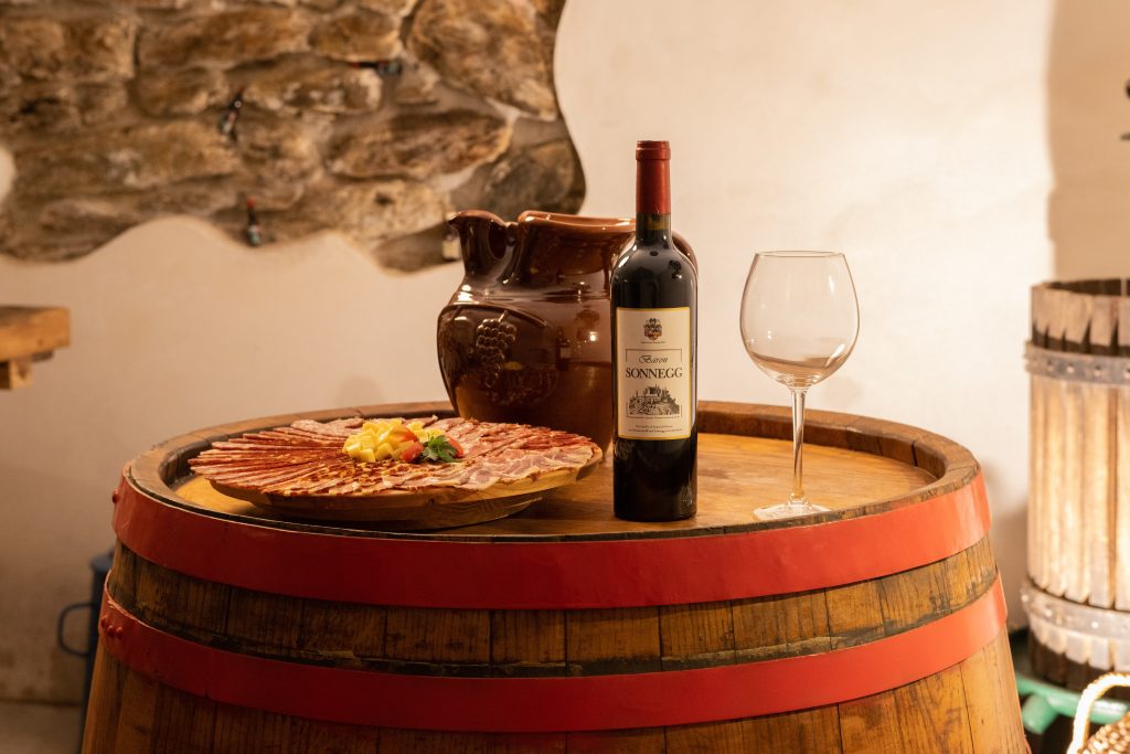 Homemade cold cuts and a bottle of red wine on a barrel