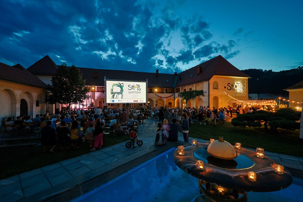 An evening open-air film experience in the setting of a historic castle courtyard.