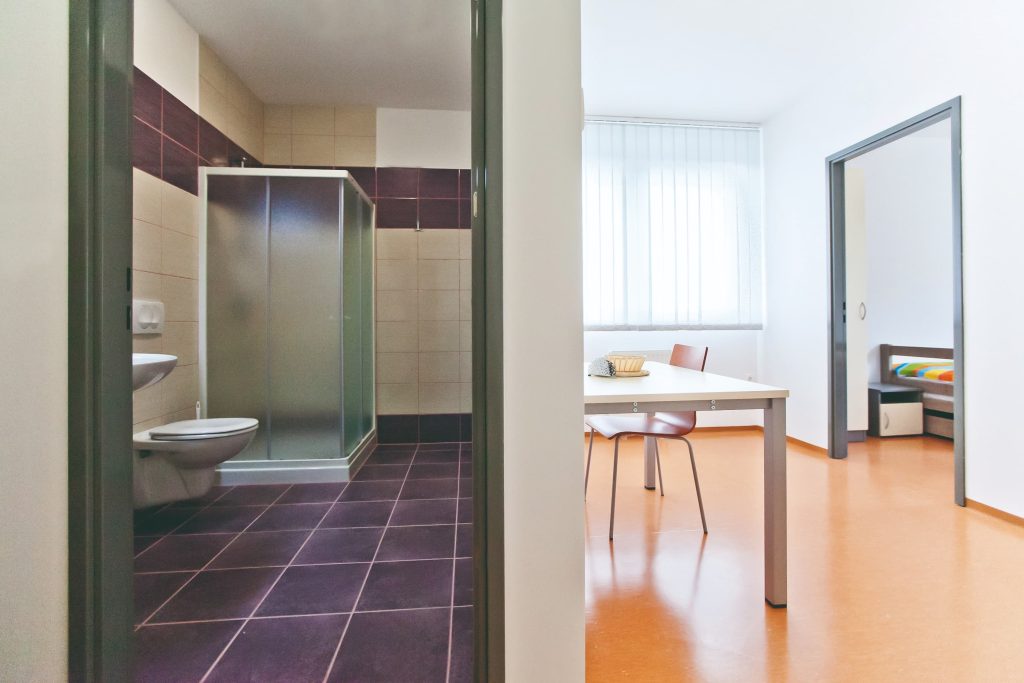 A bright multi-bed room with a table and bathroom