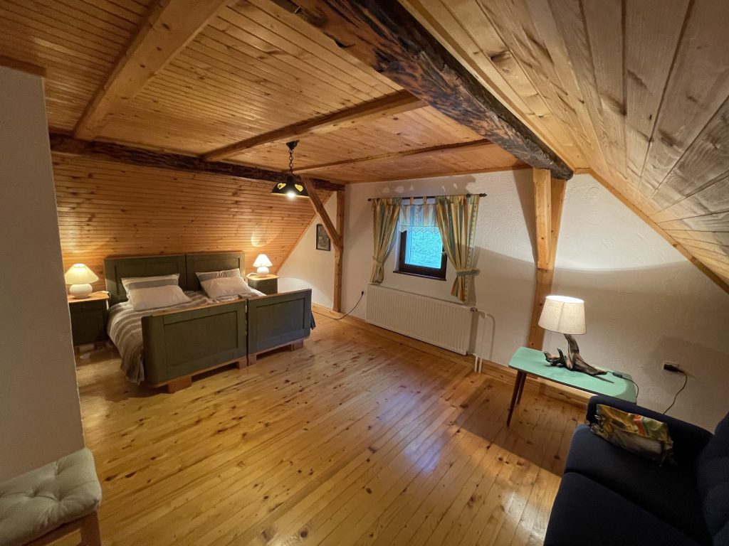 A large, spacious bedroom with wooden ceilings and a bed.
