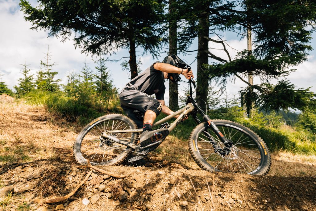 A cyclist enjoys a dynamic ride on a forest path, where the varied terrain and natural environment offer a true experience for mountain biking enthusiasts.