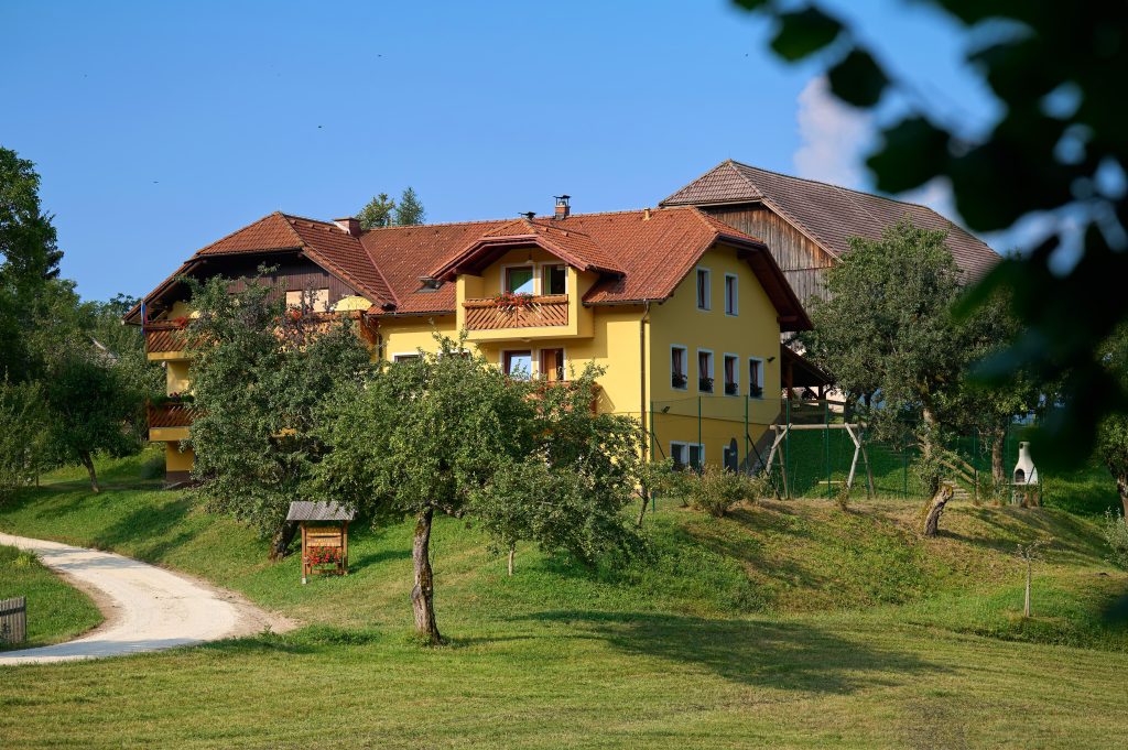 Gradišnik Organic Tourist Farm in Jamnica above Prevalje, surrounded by an orchard, greenery, and peaceful nature.