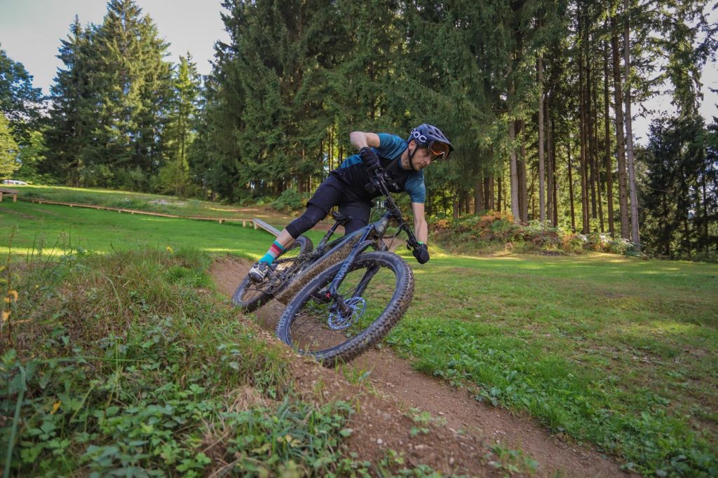 Kolesar med dinamično vožnjo skozi zavoj na progi na bike parku.
