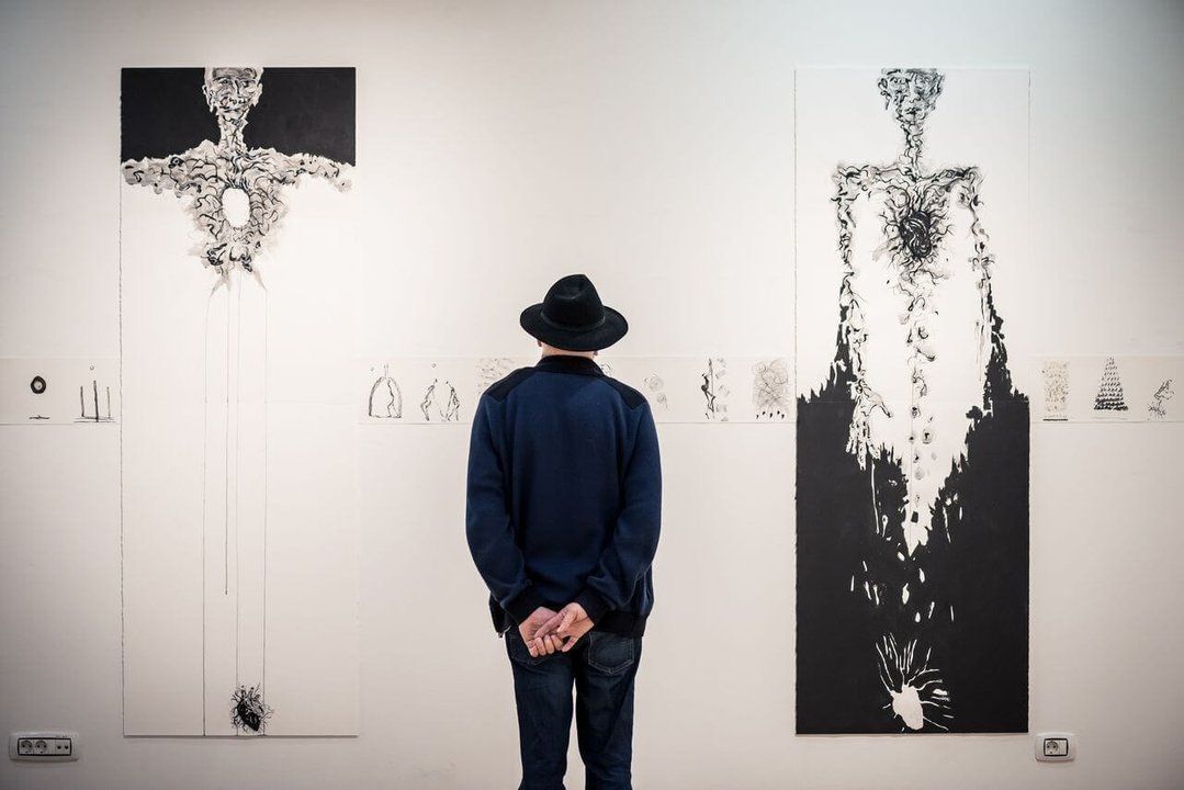 A visitor in dialogue with a work of art, where the gallery space becomes a place for observation, reflection, and the experience of art.