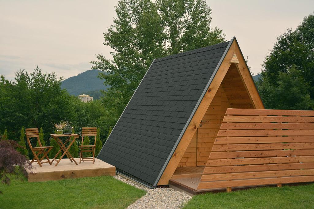 Lesena glamping hiška s prijetno teraso, mizo in stoloma.