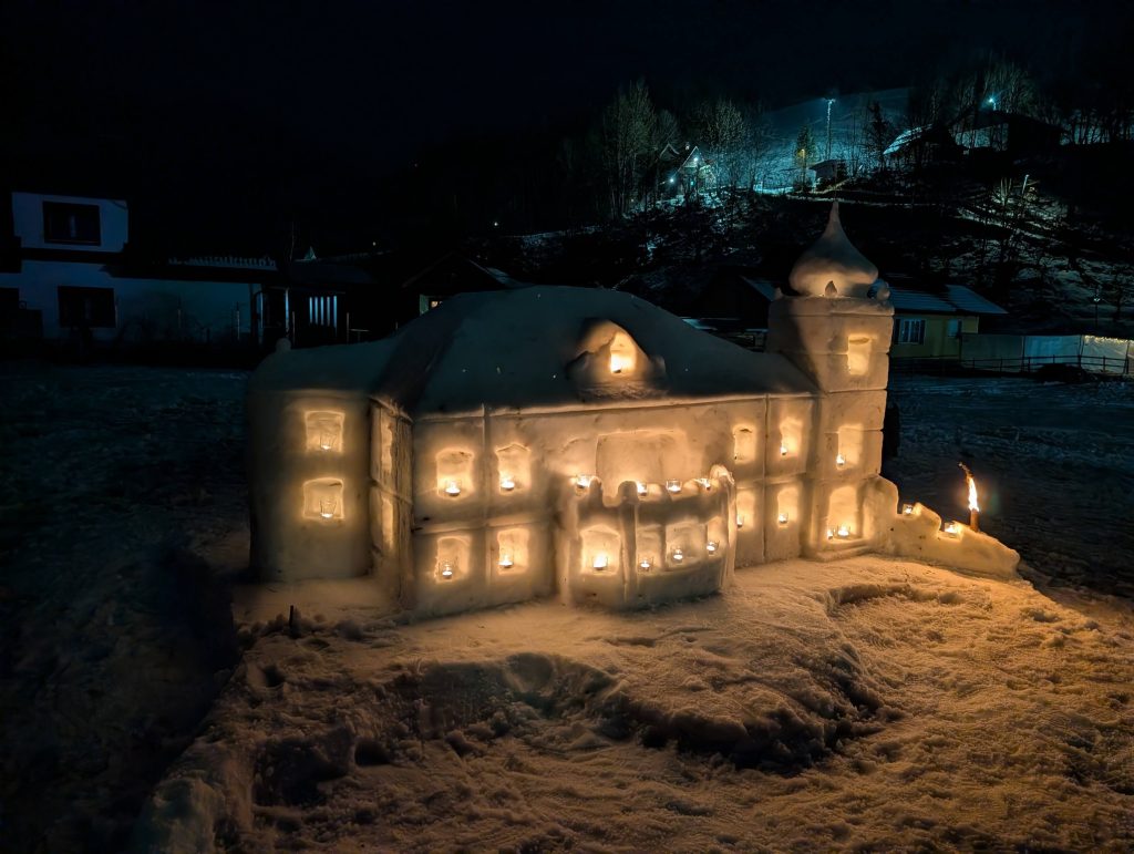 Snow castles glow in the evening in the magical light of numerous candles.