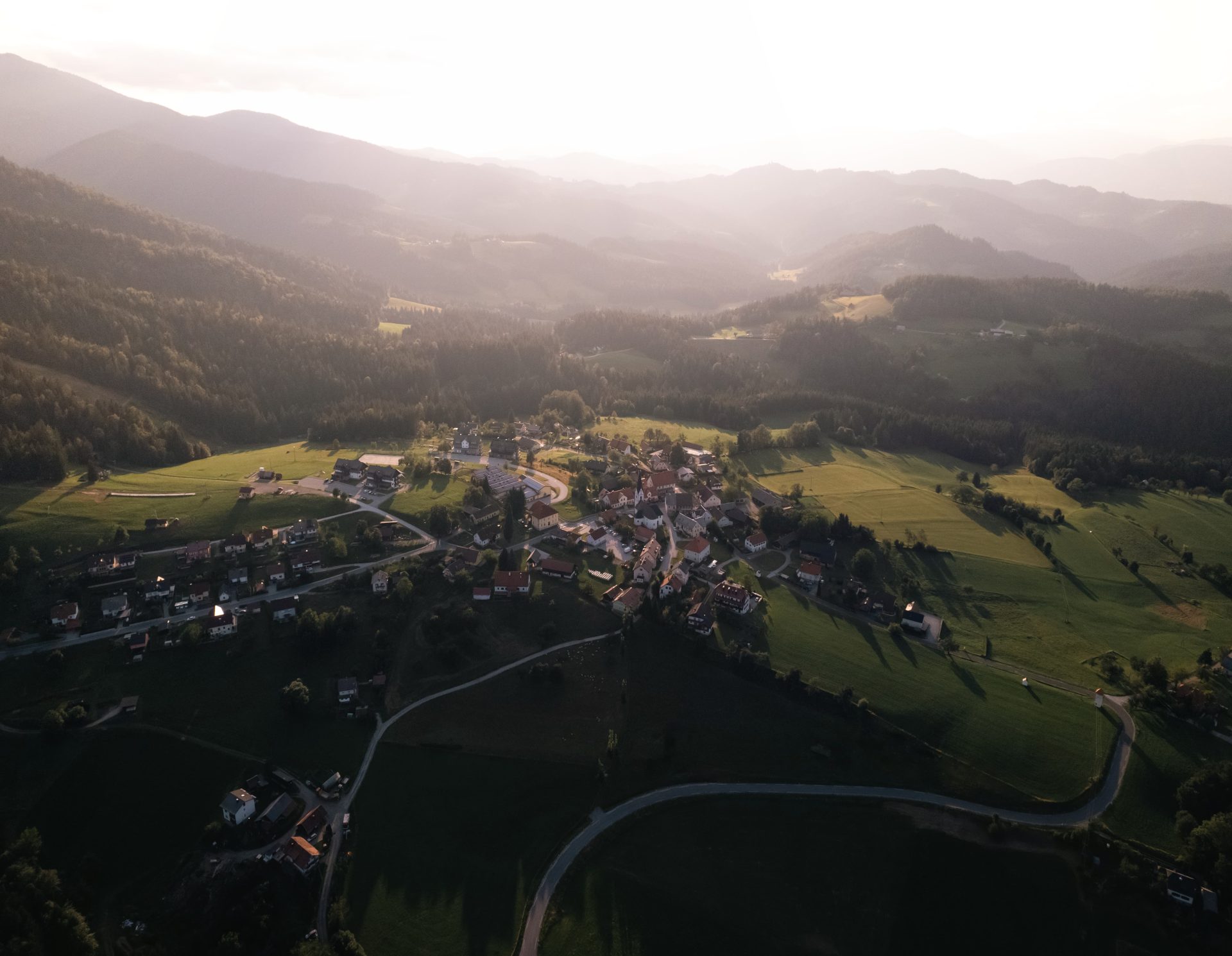 Pogled iz zraka na vaško jedro Ribnice na Pohorju, obdano z zeleno in slikovito pohorsko naravo.