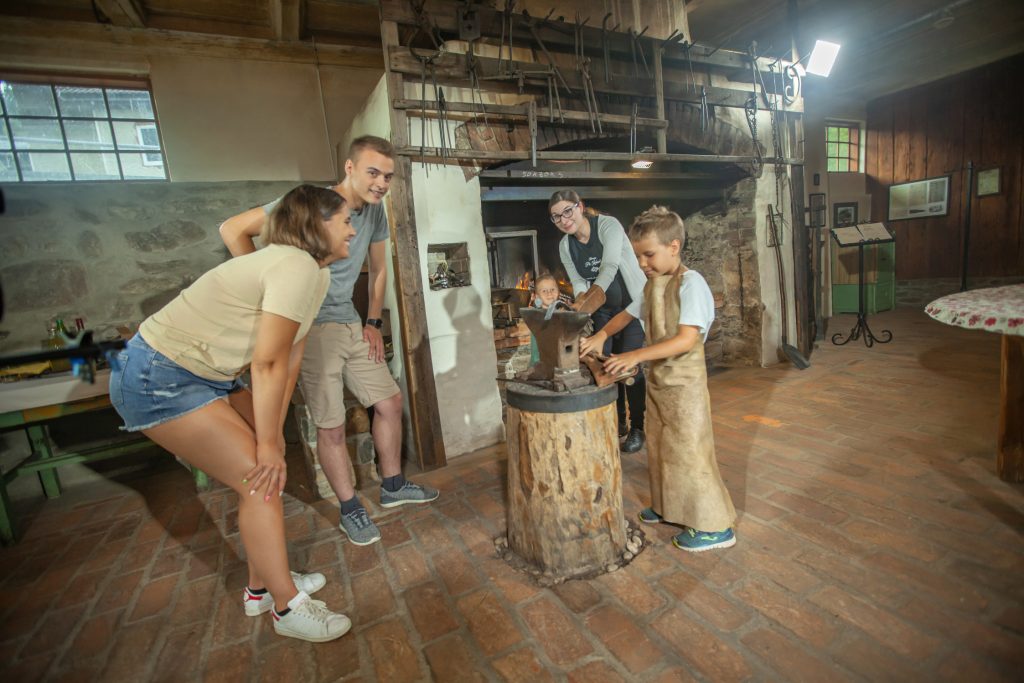 Visitors during a tour of the smithy learning about blacksmithing heritage, old tools, and the former way of working.