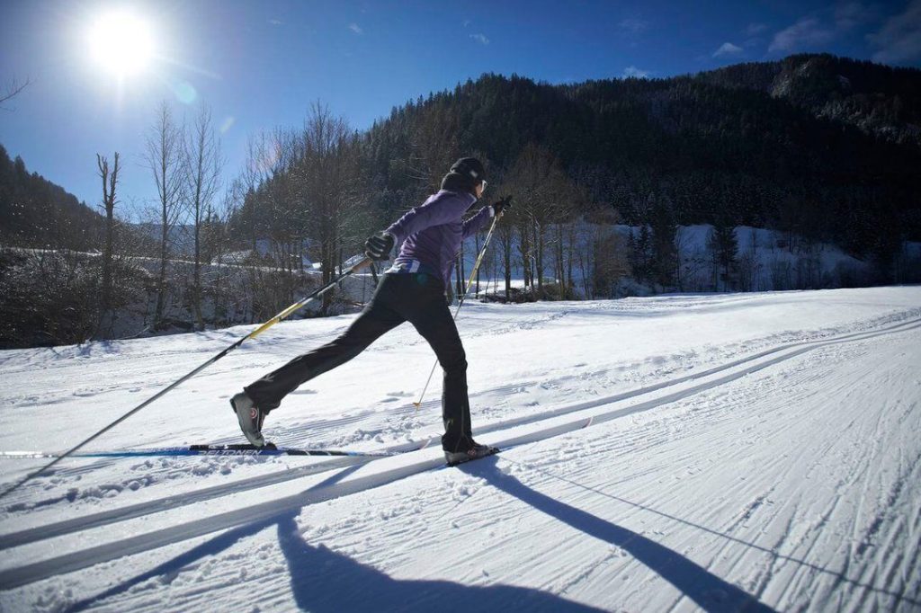 Across the snow-covered landscape on cross-country skis under the winter sun.