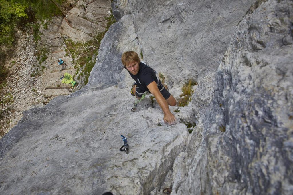 A climber sport climbing on a rock face, secured with a rope and climbing gear.