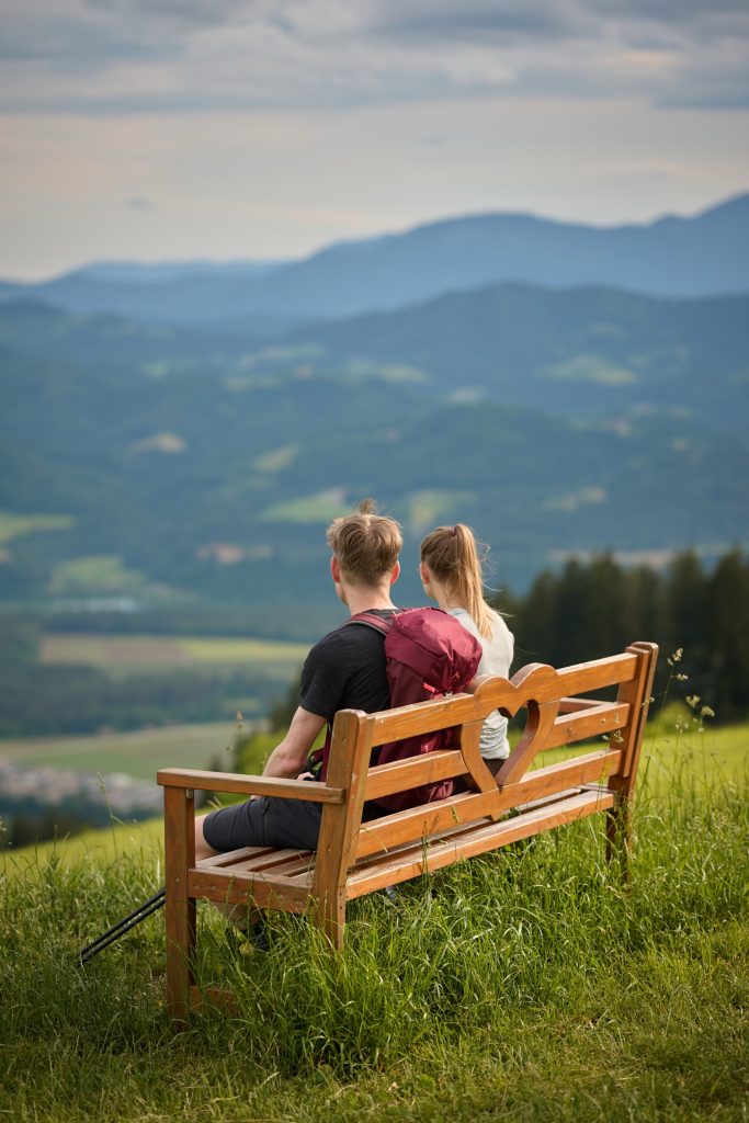 Hikers on a bench enjoying the view from St. Primož above Muta.